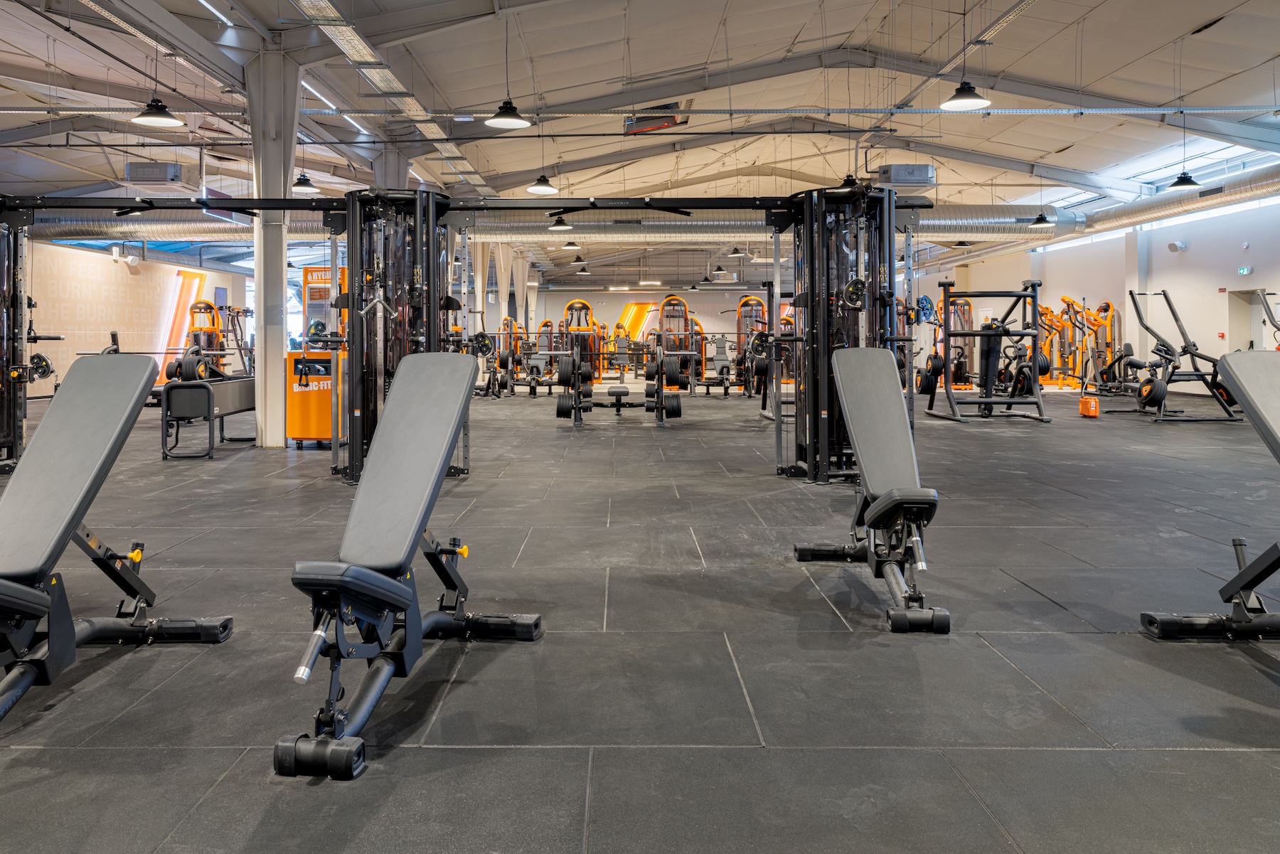 Aménagement salle de sport Basic-Fit Mérignac – zone musculation avec bancs et stations guidées Aménagement salle de sport Basic-Fit Mérignac – zone musculation avec bancs et stations guidées
